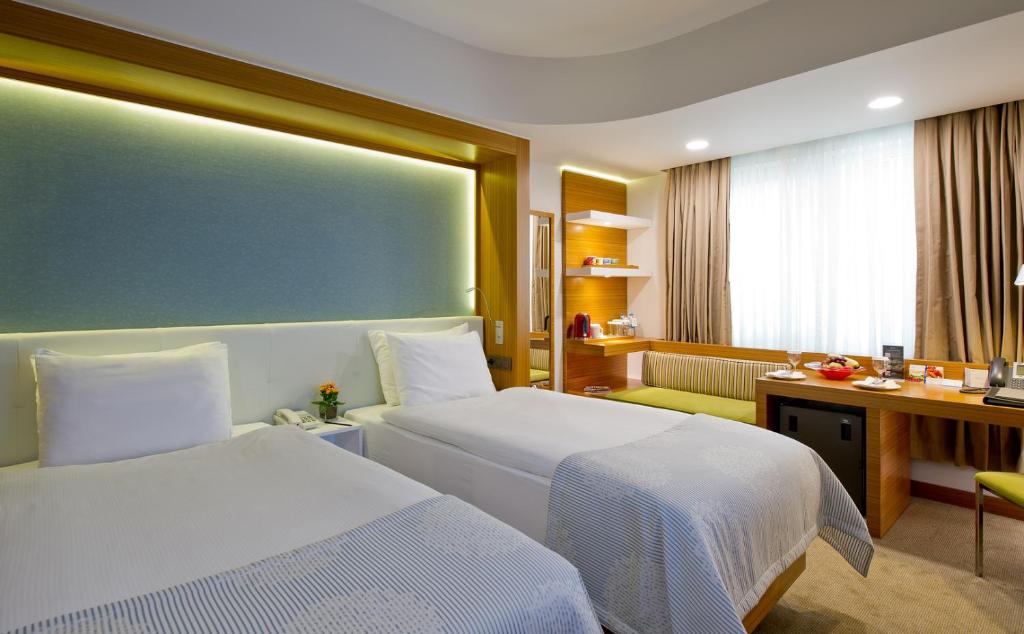 a hotel room with two beds and a desk at Divan Istanbul City in Istanbul