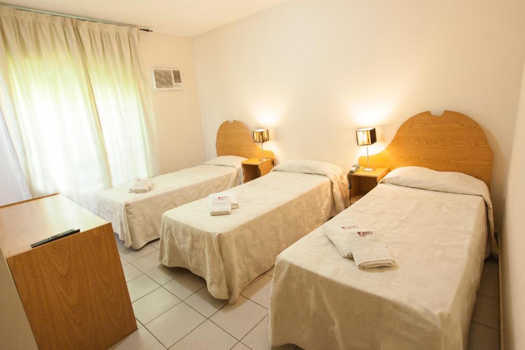 a hotel room with three beds and a window at Bonito Hotel in San Rafael