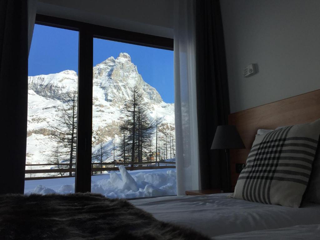 BASE CAMP alpine apartments في بيريول تشيرفينيا: غرفة نوم مطلة على جبل مغطى بالثلج