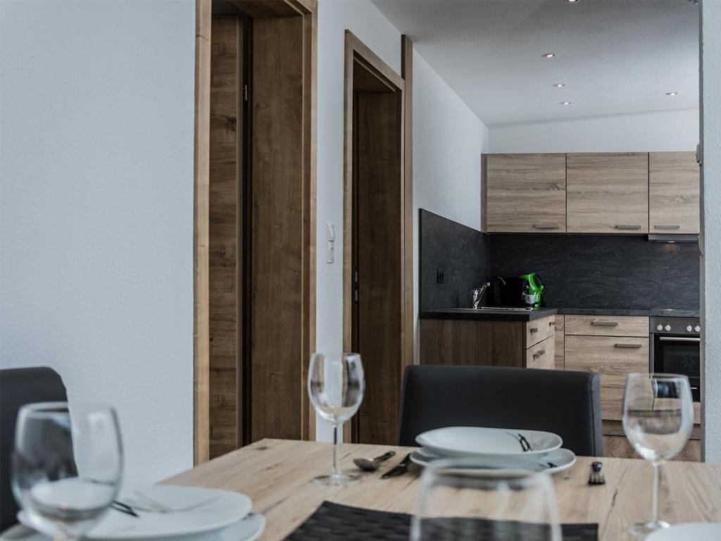 a dining room with a wooden table with wine glasses at Alpenapart Frank in Längenfeld