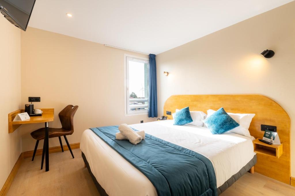 a bedroom with a large bed with blue pillows at Logis Hôtel & Restaurant Cap Hôtel in Noyelles-Godault