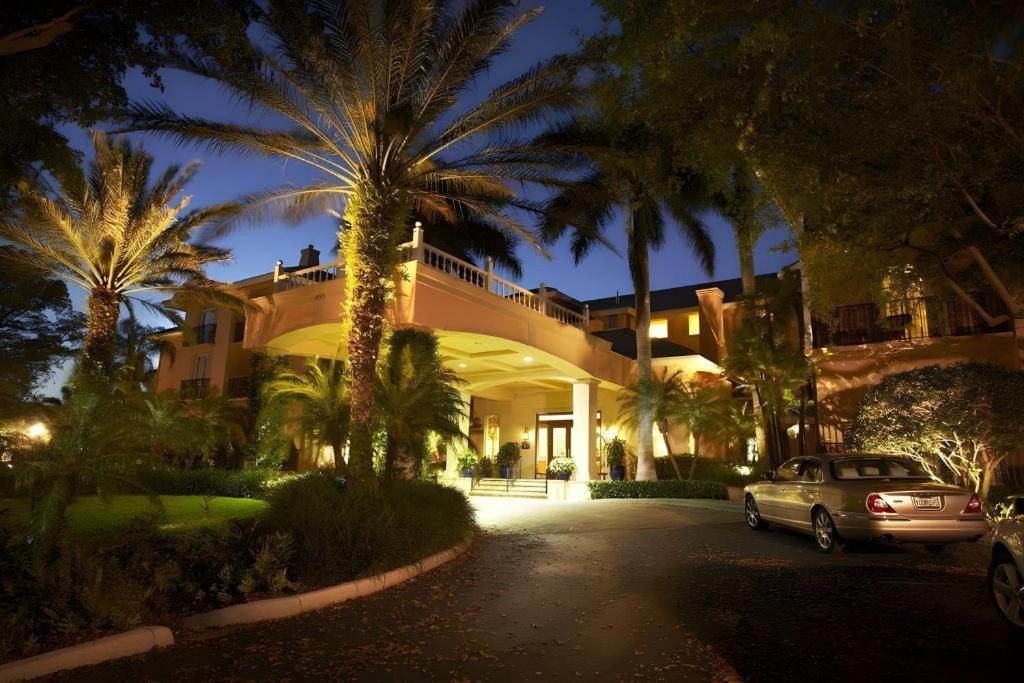 a car parked in front of a house with palm trees at The Capri Inn in Naples