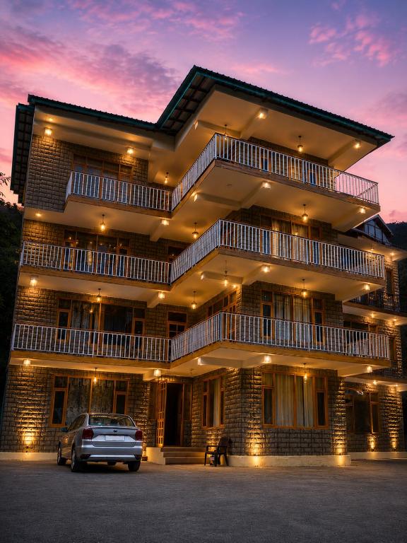 a building with a car parked in a parking lot at Crest Manali River View in Manāli