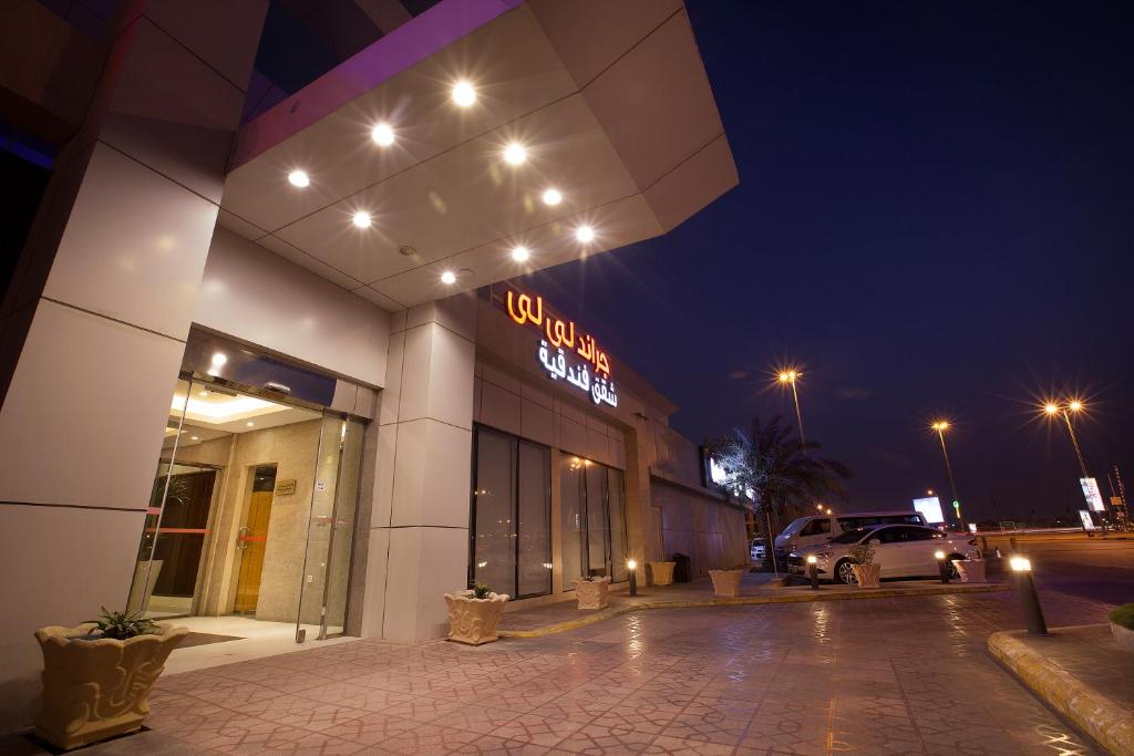 a building with a neon sign in a parking lot at Grand Lily Hotel Suites in Al Hofuf