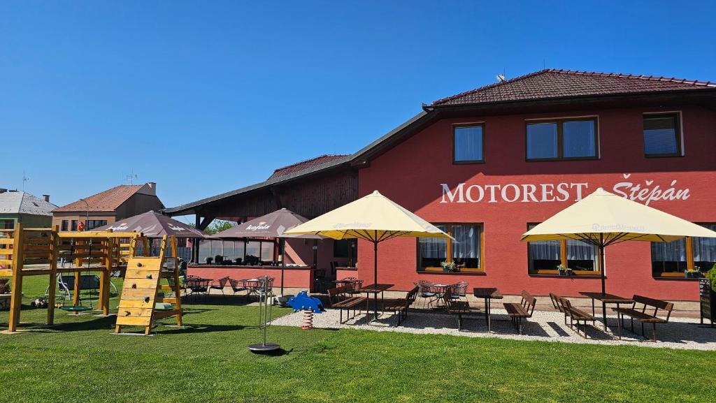 a building with a playground with tables and chairs and umbrellas at Motorest Štěpán in Těšov