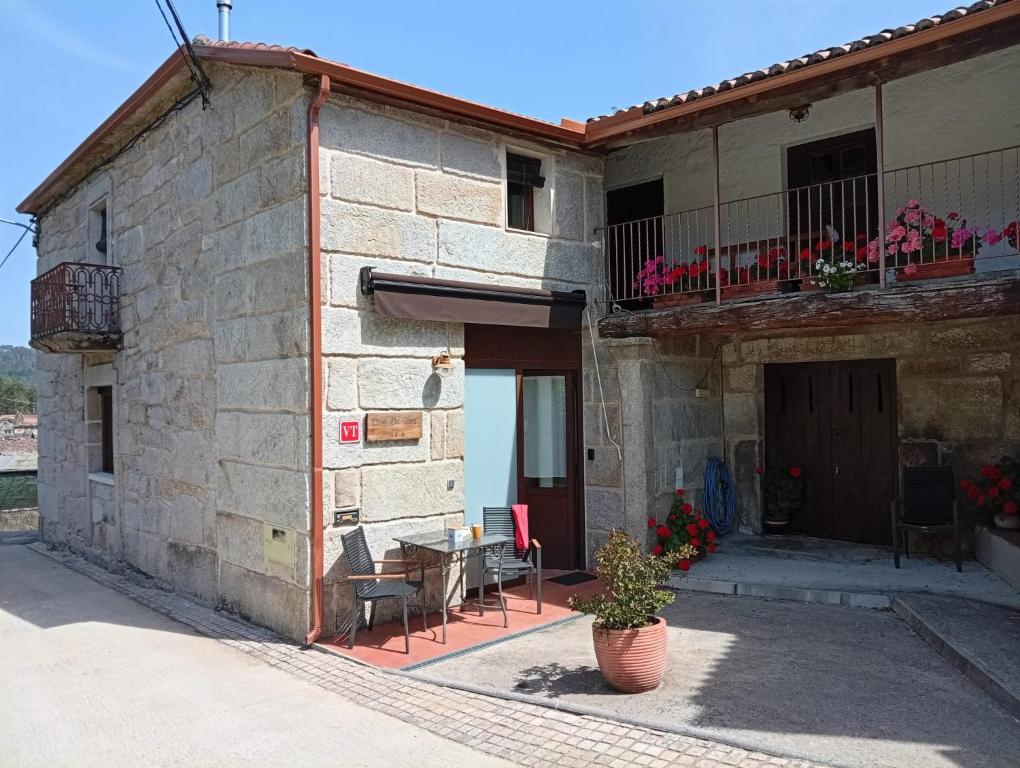 a building with a table and chairs in front of it at Casa da Eira in Lobios