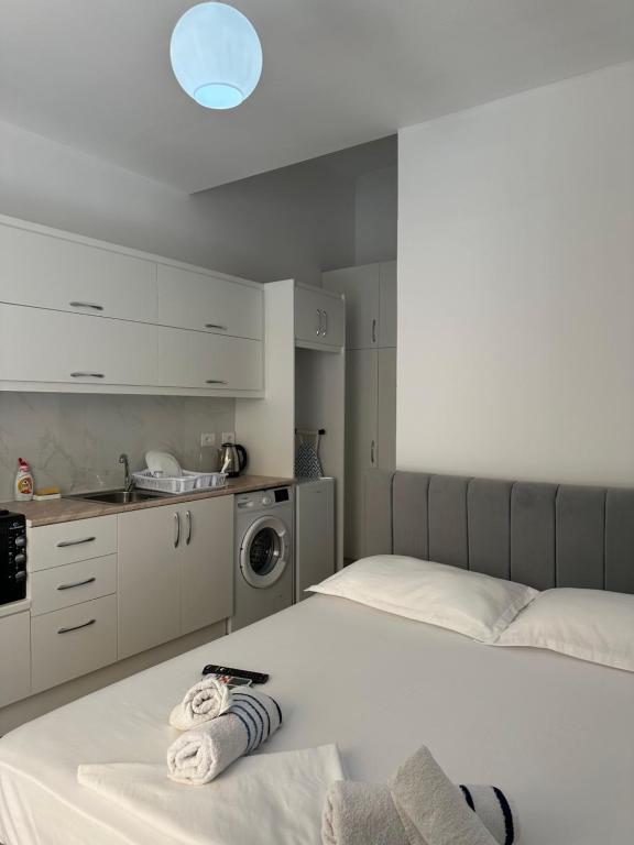 a white bedroom with two beds and a kitchen at Adela's Saranda Central Apartment in Sarandë