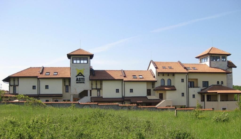 a large building with two towers on top of a field at Asti Arthotel in Sinemorets