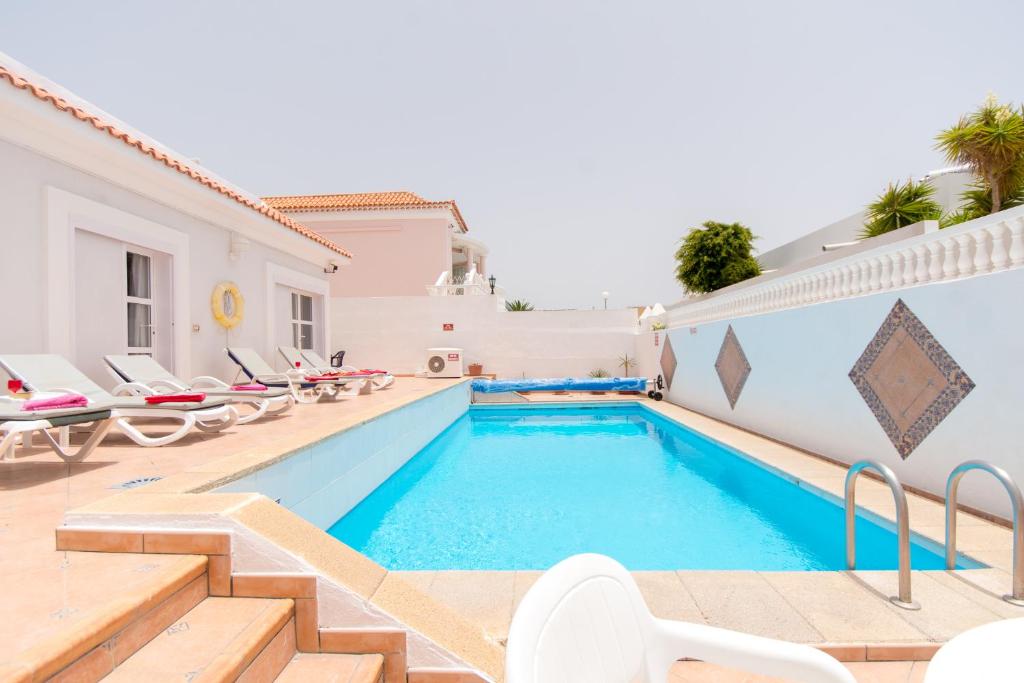 a villa with a swimming pool and lounge chairs at Lovely 4 Bedroom Holiday Villa in Callao Salvaje