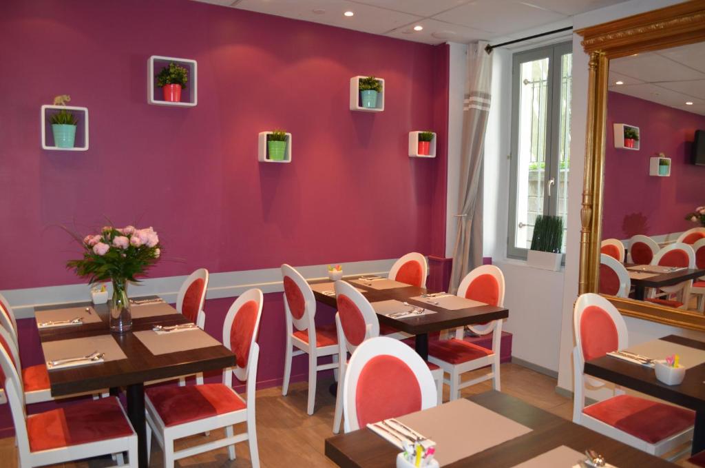 a restaurant with purple walls and wooden tables and chairs at Hôtel Les Corps Saints in Avignon