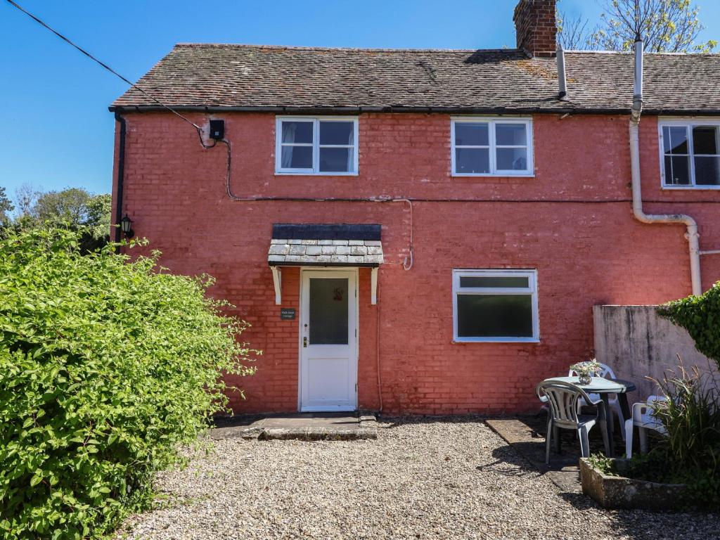 a red brick house with a white door at Walk Farm Cottage in Gloucester