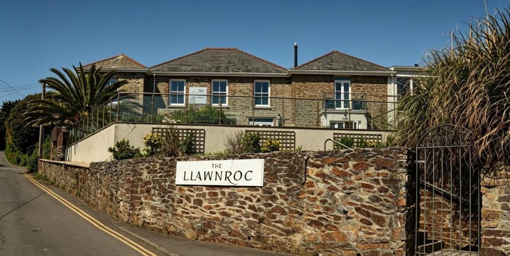 a sign on a stone wall in front of a house at The Llawnroc Hotel in Gorran Haven