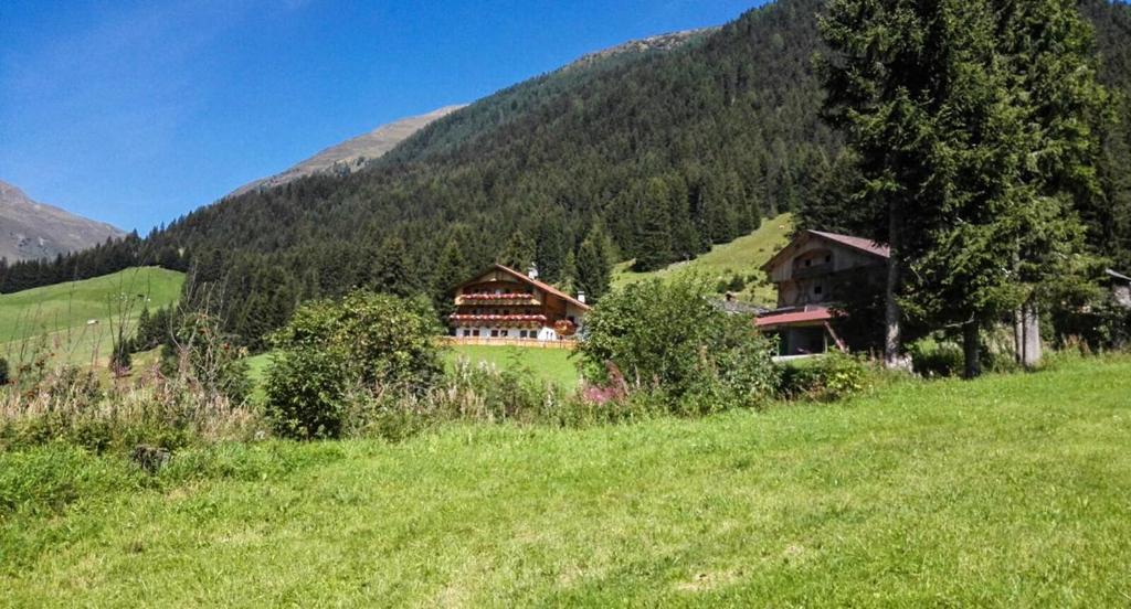 ein Haus auf einem Hügel auf einem Grasfeld in der Unterkunft Burgerhof in Santa Maddalena in Casies