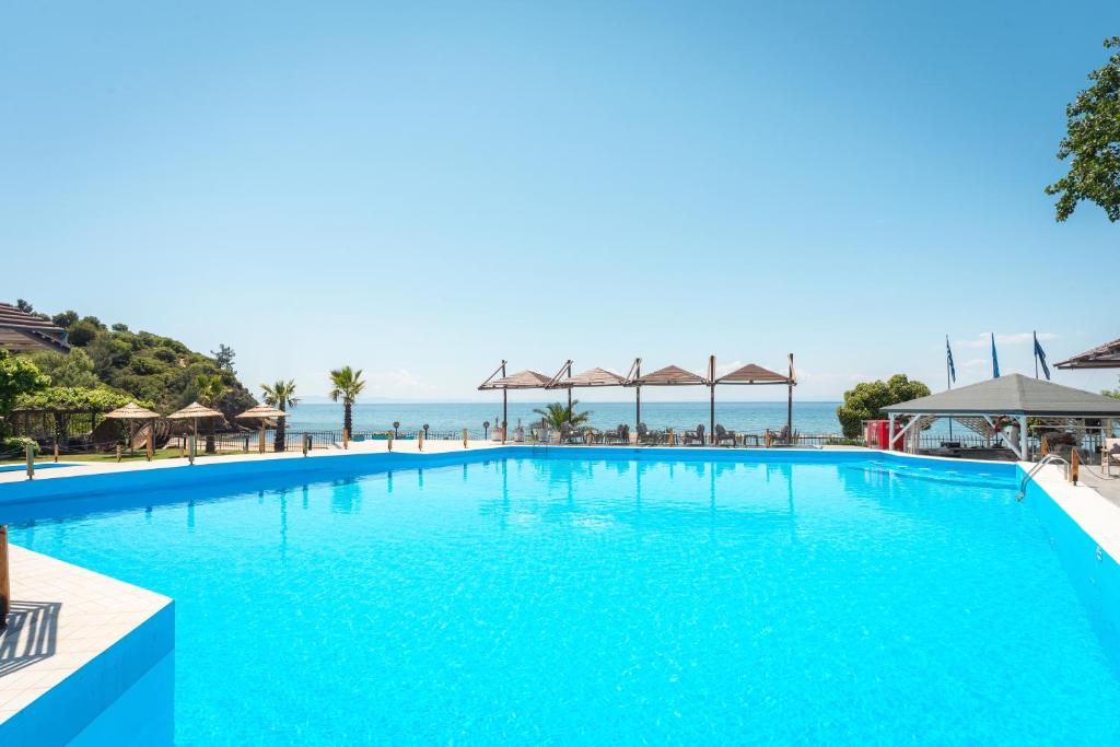 a large blue swimming pool with the ocean in the background at Kamari Beach Hotel in Potos