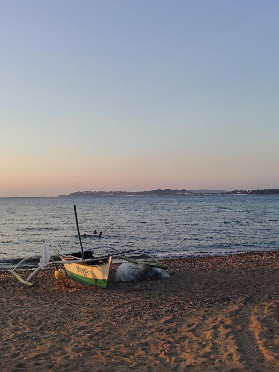 a boat sitting on a beach next to the water at Hangout Beach Resort in Caticlan
