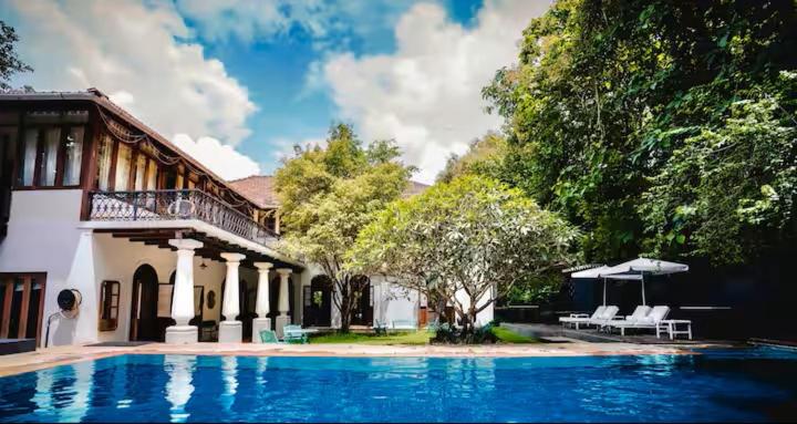 a large swimming pool in front of a house at Birdsong,Goa in Tivim
