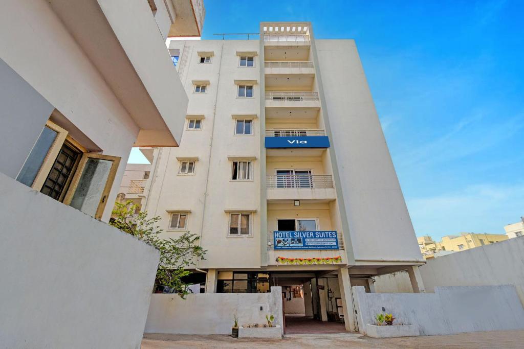 a tall white building with a blue sign on it at Via Silver Suites in Hyderabad