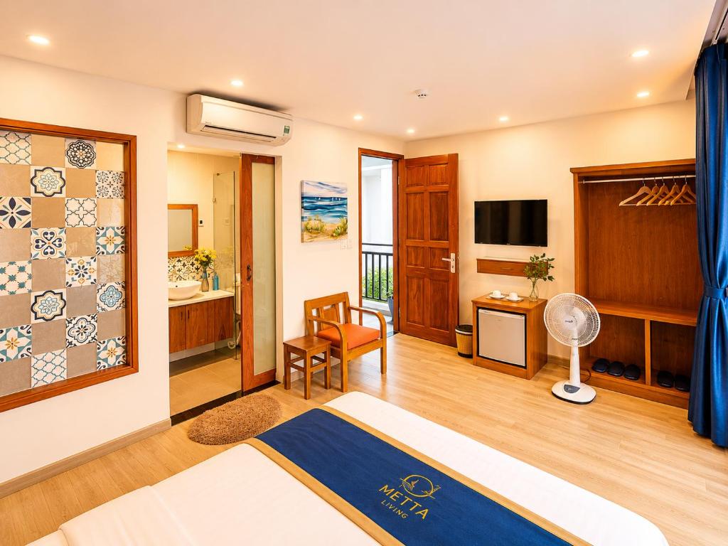 a hotel room with a bed and a television at Metta Living Hoi An in Thanh Ðông (1)