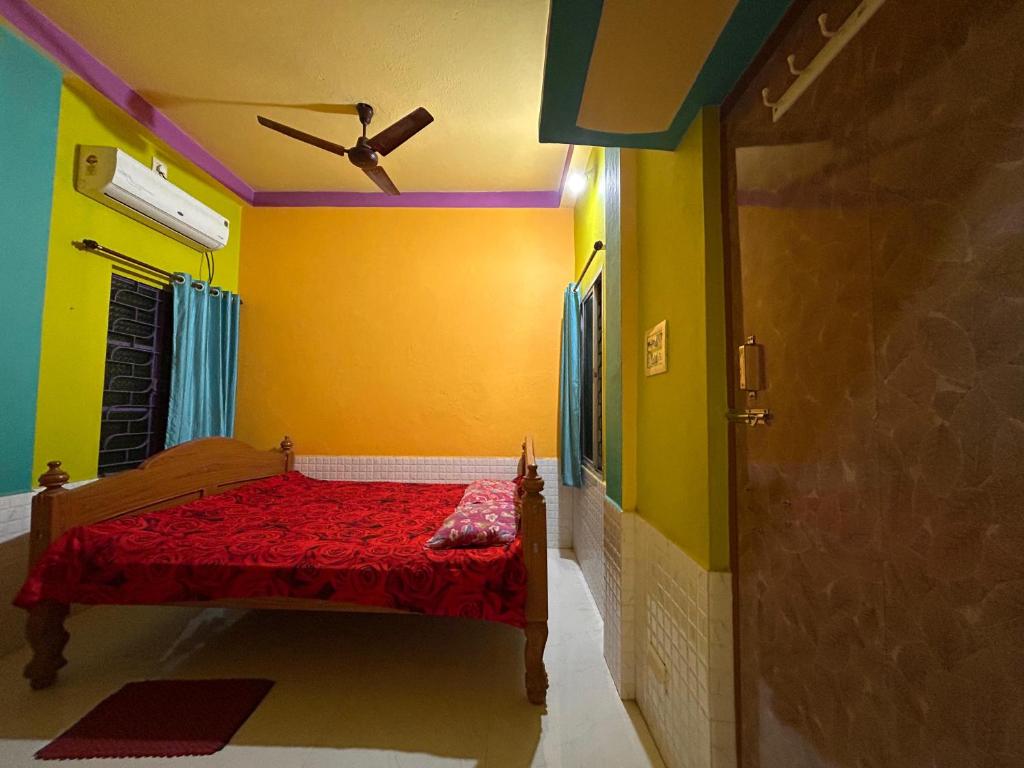 a bedroom with a bed with red sheets and yellow walls at Sundarban Residential Hotel in Pātharpratima Island