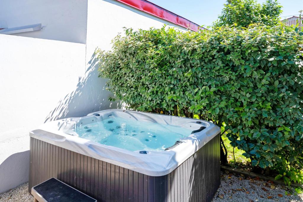 a hot tub in a garden next to a bush at Maison Cosy Bohème Chic Biarritz in Biarritz
