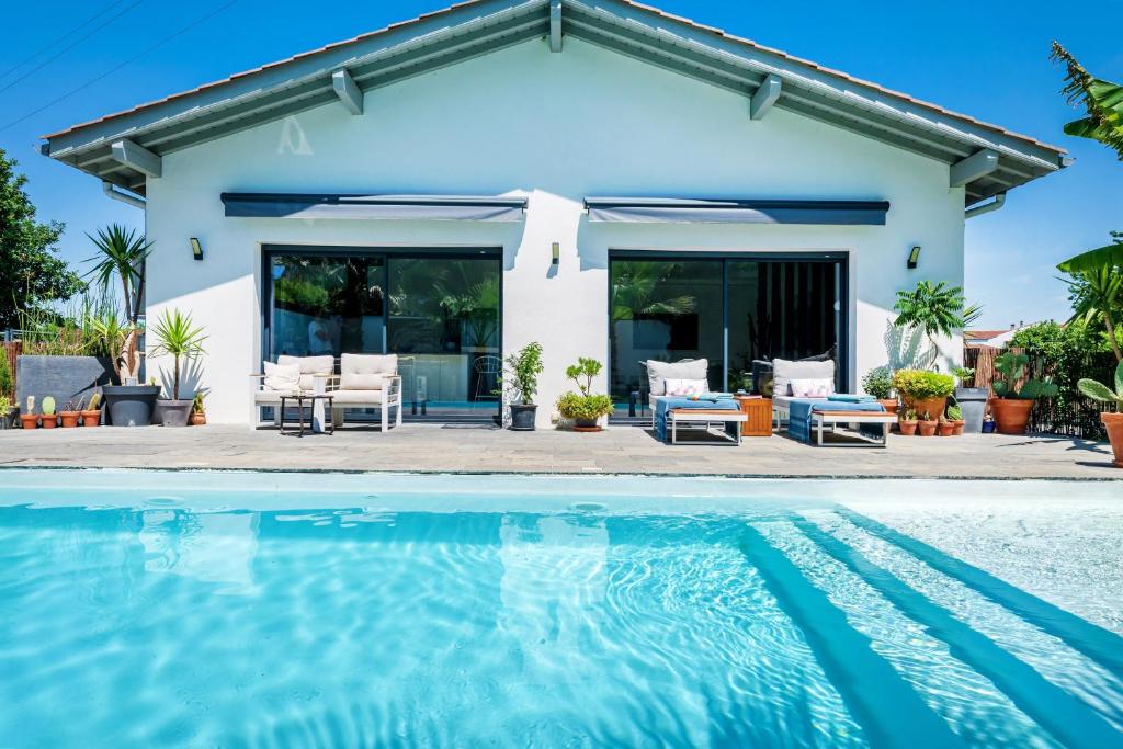 a villa with a swimming pool in front of a house at Chambre D'hôtes Villa Menta in Arbonne