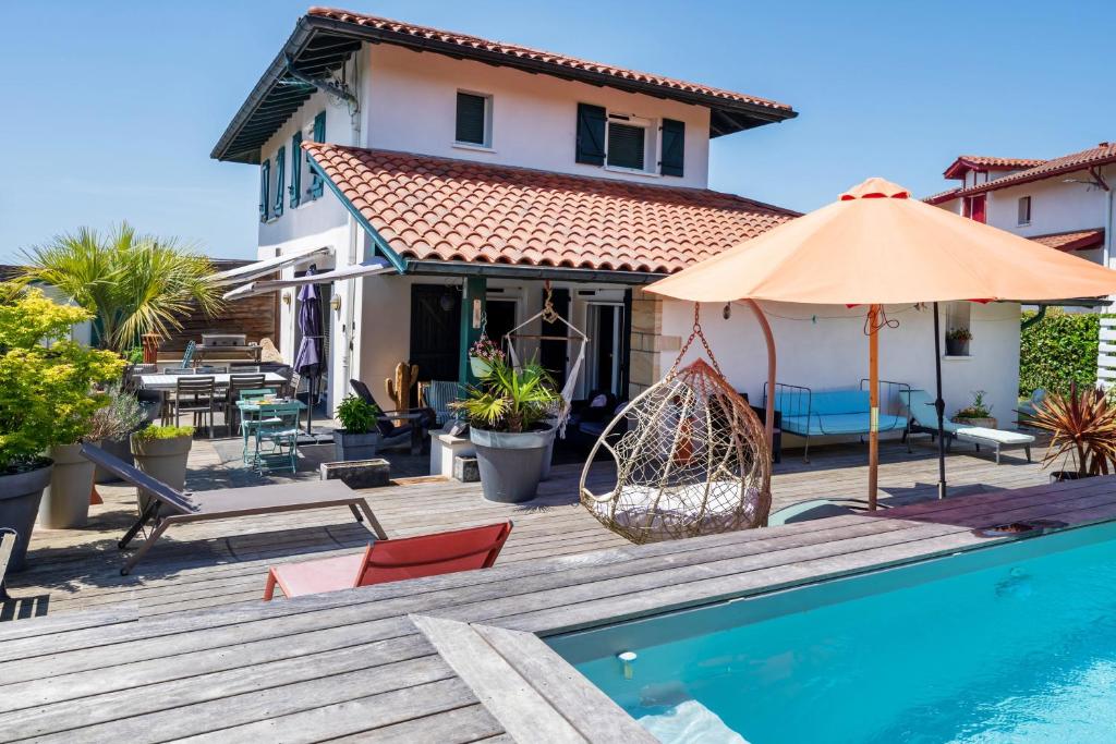 a house with a swimming pool and an umbrella at Chambre d'hôtes Ganttipienea in Ahetze