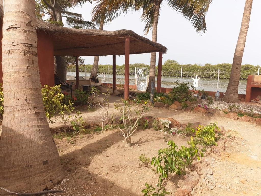 a pavilion with a palm tree in a garden at Lasofia in Mbodiène