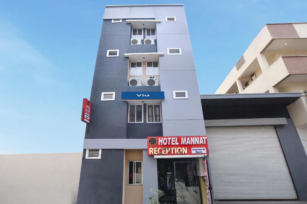 a tall grey building with a sign in front of it at Via Mannat in Indore