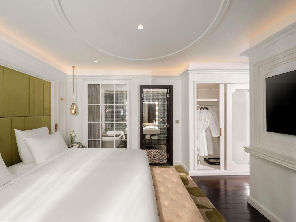 a bedroom with a large white bed and a tv at Hotel de l'Opera Hanoi - MGallery in Hanoi