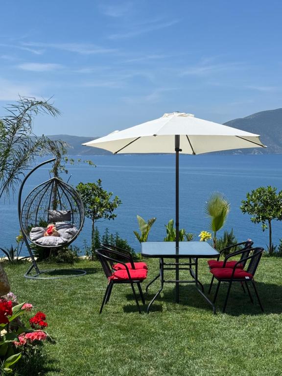 a table and chairs with an umbrella and a swing at Sebi's Chalet with Sea View in Vlorë