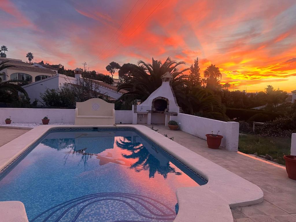 a large swimming pool with a sunset in the background at Villa Casa Para Ti in El Tosalet