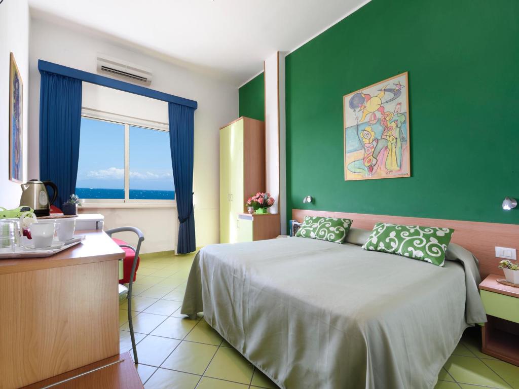 a bedroom with a bed and a green wall at Alta Marea Sorrento in Massa Lubrense
