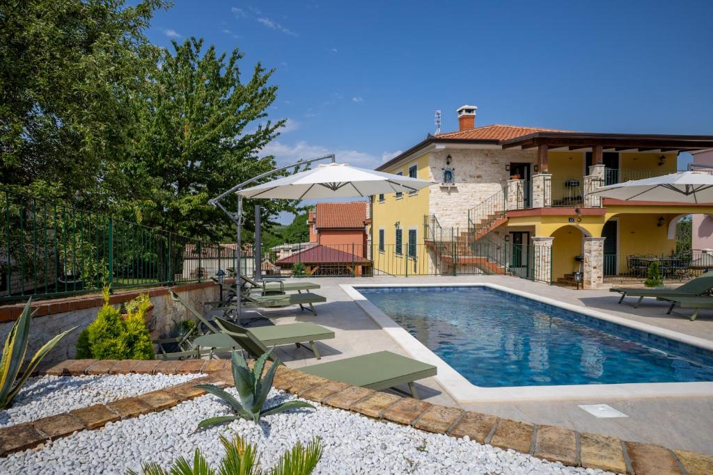 a pool with chairs and umbrellas next to a house at Ivana in Karpijan in Umag