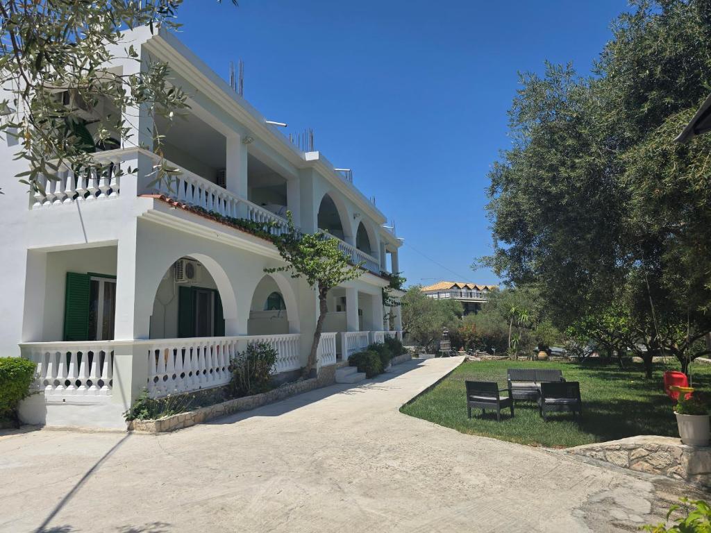 a white building with a bench in front of it at Mersina Apartments in Keri
