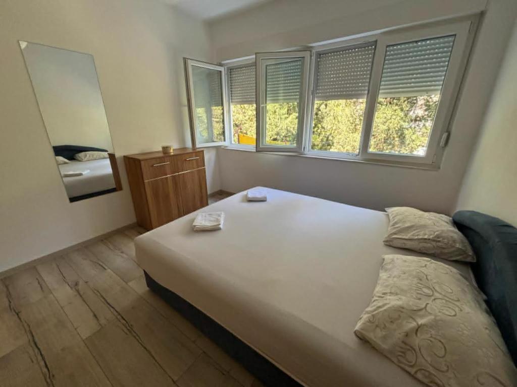 a bedroom with a large white bed and windows at Parking free in Mostar