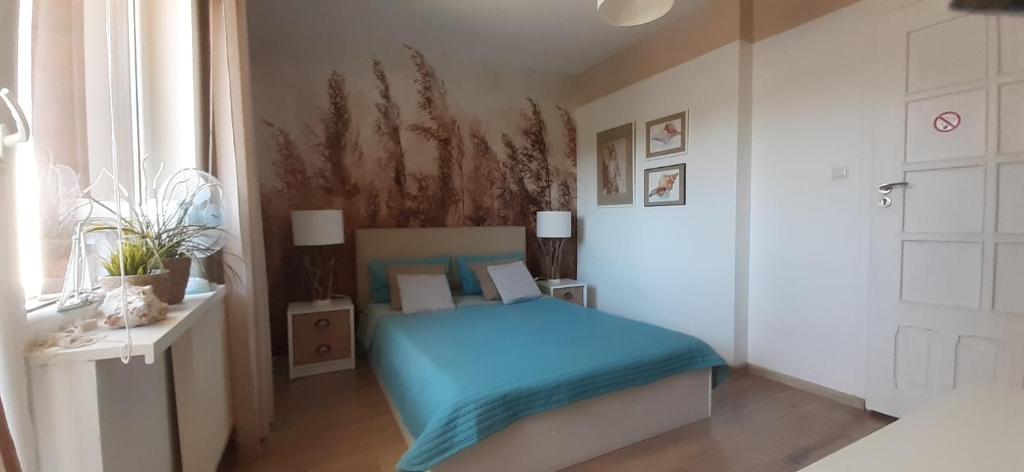 a bedroom with a blue bed and a window at Biały Domek in Stegna