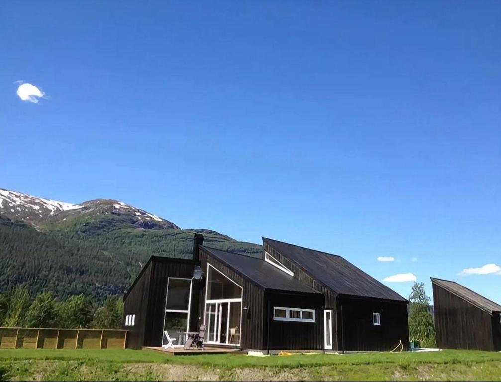 a black house with mountains in the background at Exclusive Designer Cabin - Panoramic Mountain View in Vossevangen