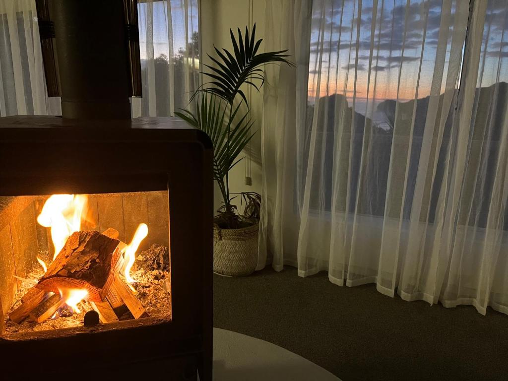 a fireplace in a room with a view of a window at Sunbird House Piha in Piha