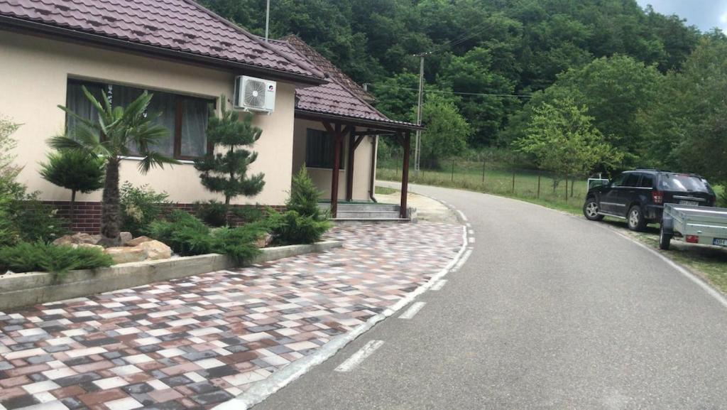 a house with a road next to a car at CASA CODRILOR - Greencodru liniste si relaxare in Codru