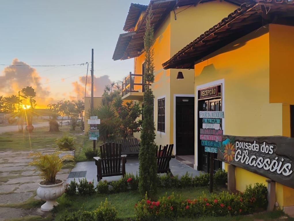 a building with chairs and a sign in front of it at Pousada Dos Girassois Prado in Prado
