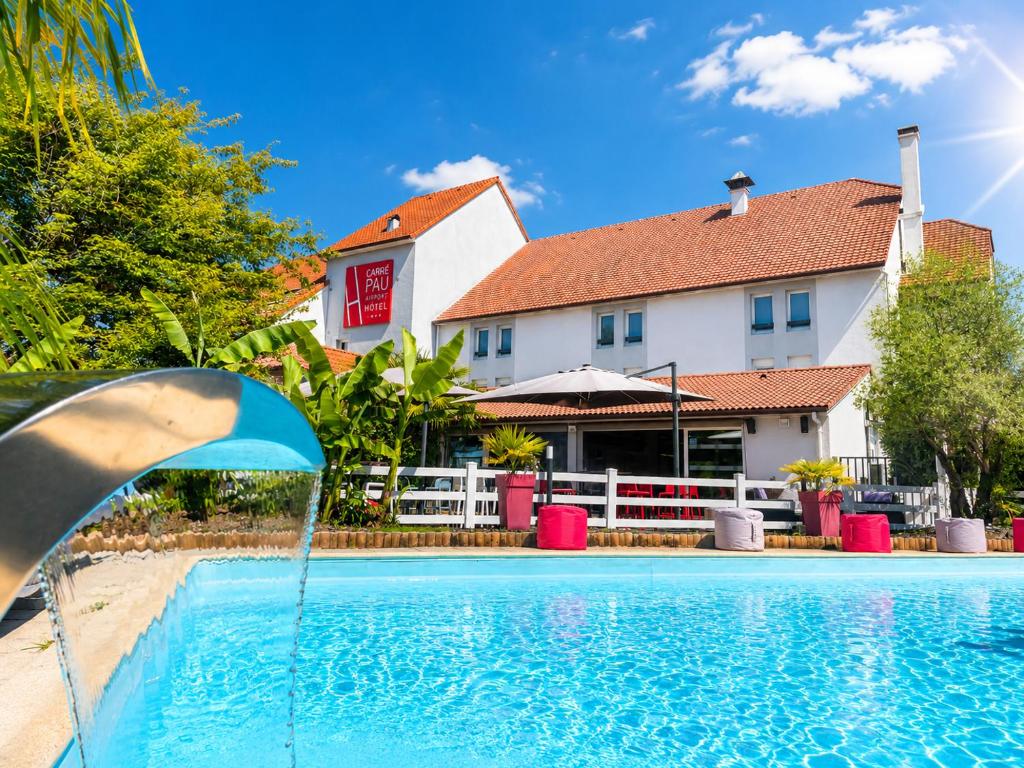 a swimming pool in front of a hotel at Carré Pau Airport Hôtel in Serres-Castet