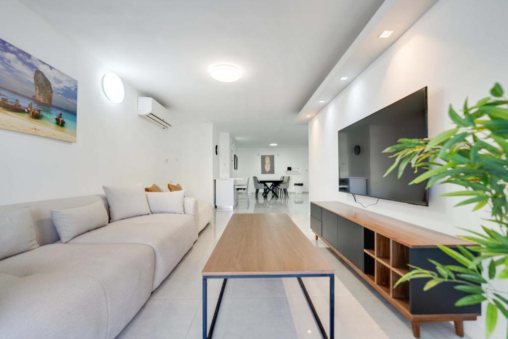 a living room with a white couch and a flat screen tv at Spacious Luxury Beach Getaway by Torohome in Ashdod