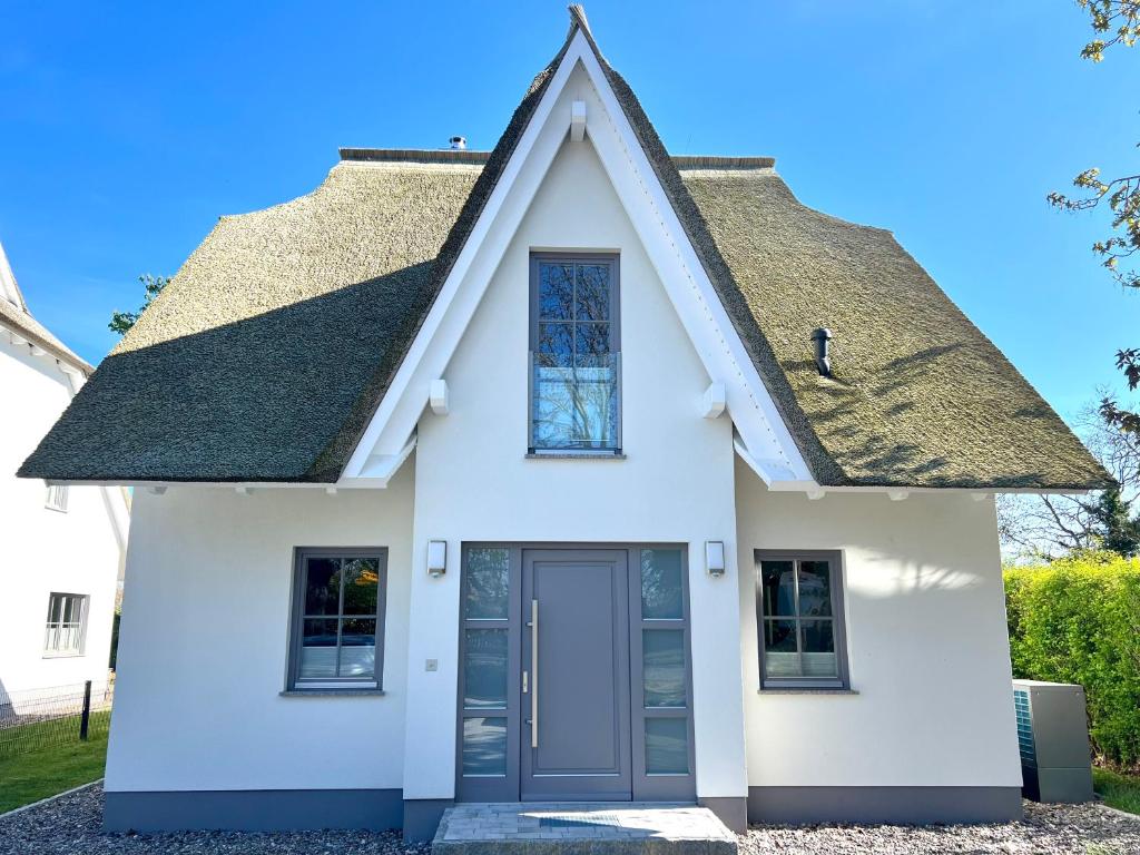 a white house with a gray roof at Ferienhaus Sundevit - exklusives Ferienhaus mit Infrarotsauna, Whirlpool-Wanne und Kamin in Putgarten