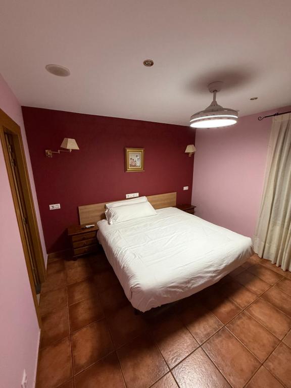 a bedroom with a white bed and a red wall at Hostal Arévacos in Soria