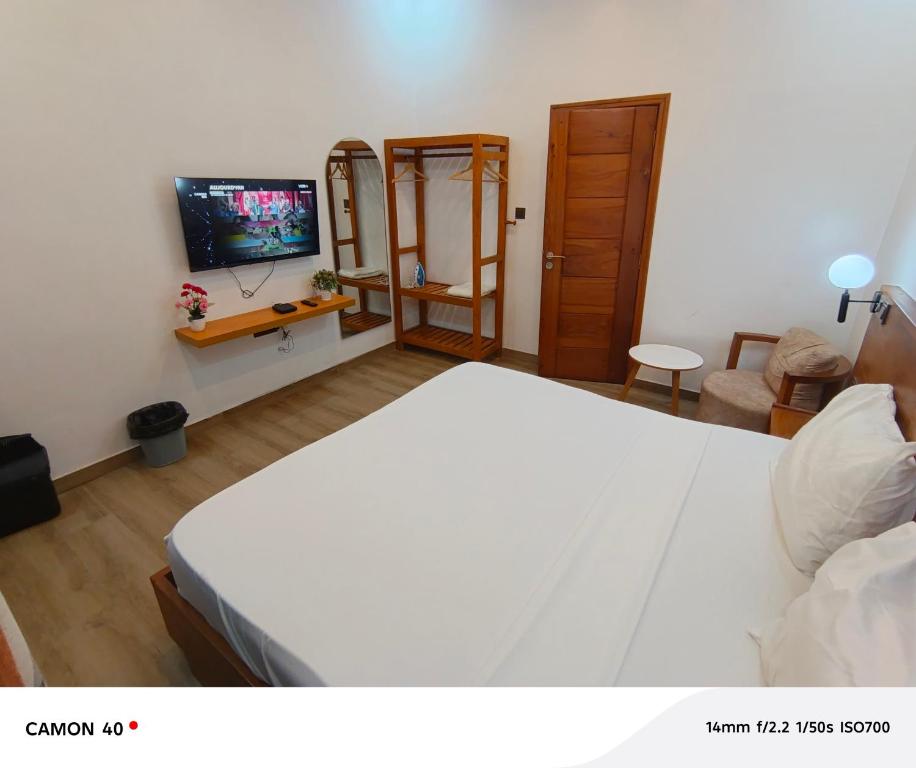 a bedroom with a large white bed and a television at Résidence saint Daniel in Cotonou