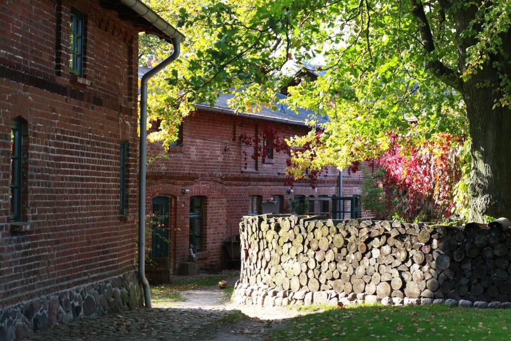 a brick building with a stone wall next to a tree at Charmante Ferienwohnung in einzigartiger Anlage - Büdnerei Lehsten in Möllenhagen