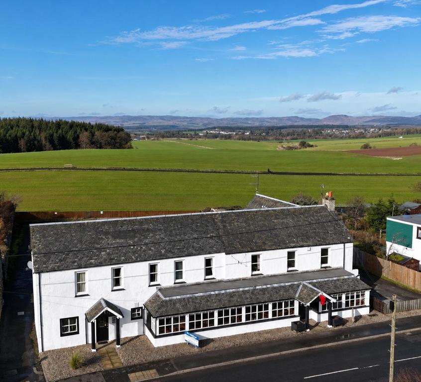 an aerial view of a white building with a green field at The Anglers Inn in Guildtown
