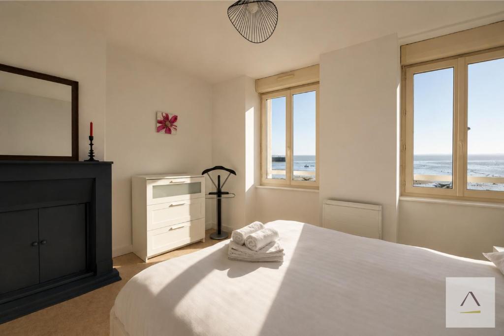 a bedroom with a bed and a tv and windows at La Maison de Pêcheurs in Cancale