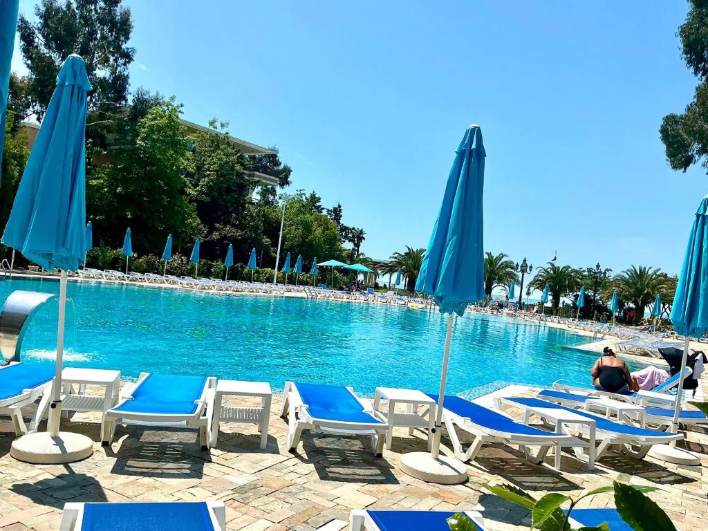 a swimming pool with chairs and blue umbrellas at Beach Dreamland Oasis in Chakvi