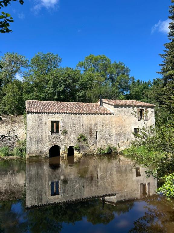 an old building sitting in the middle of a river at Le Moulin de Tiquetorte in Moulis-en-Médoc